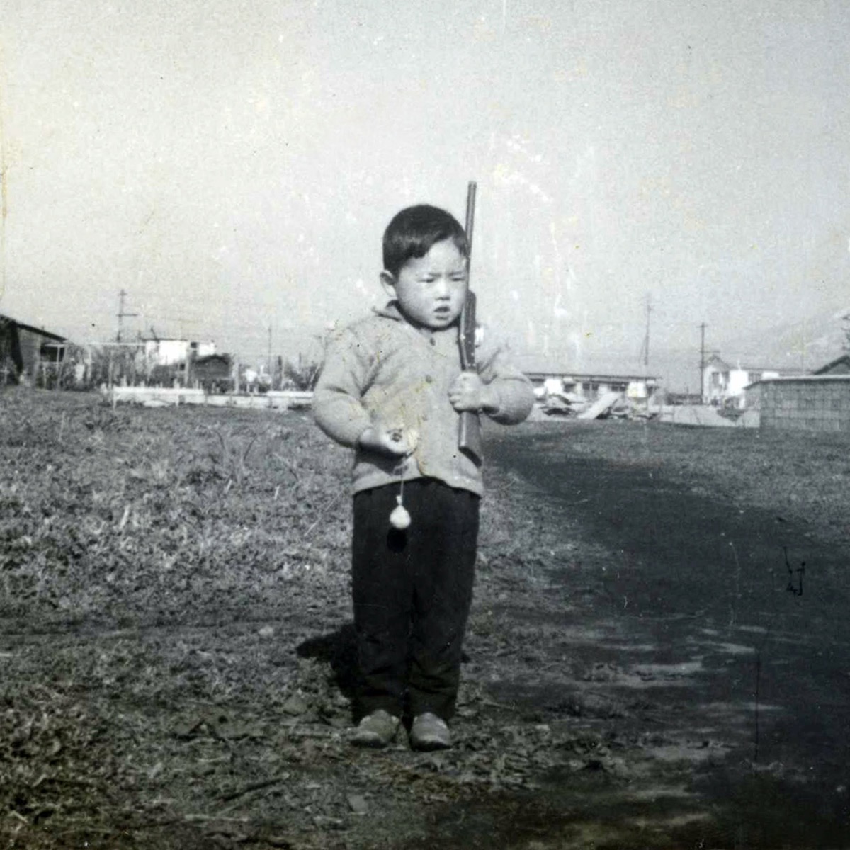 おもちゃの鉄砲を持って野原に立つ